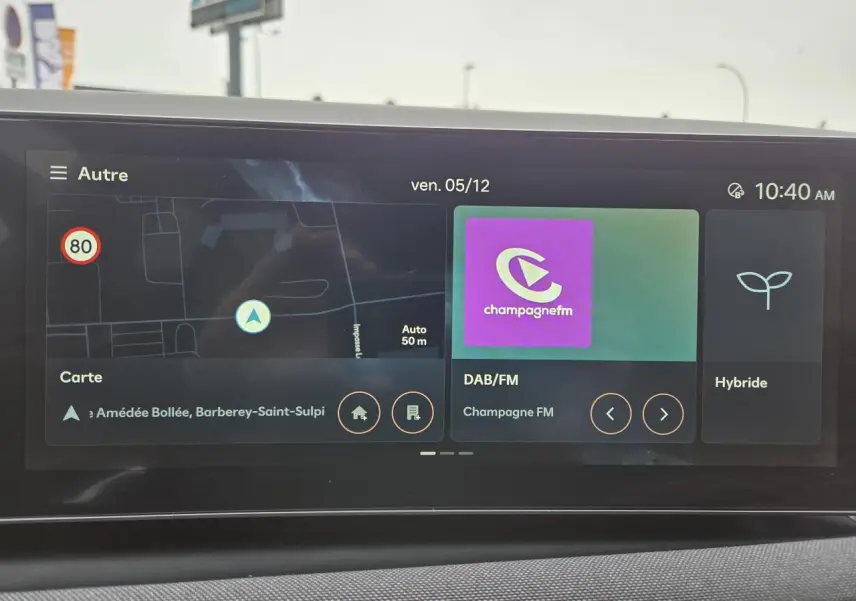 Écran tactile intérieur du Hyundai Tucson 2025 affichant navigation, radio DAB/FM et mode hybride.