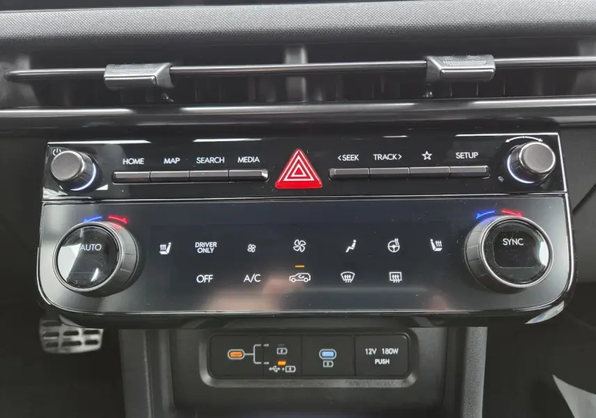 Vue rapprochée de la console centrale noire brillante du Hyundai Tucson 2025, avec commandes climatisation et multimédia.