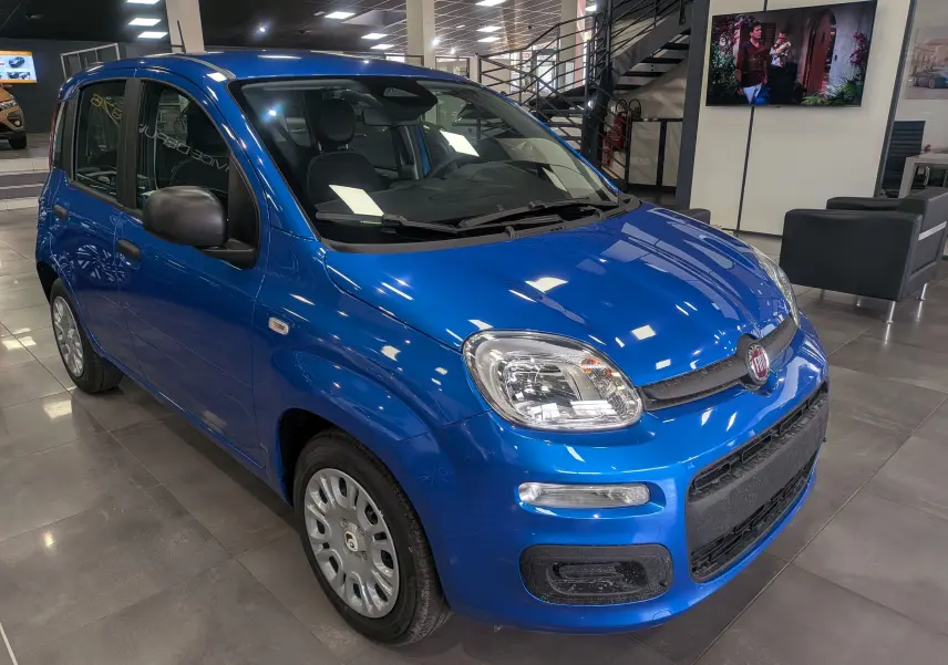 Fiat Panda 1.0 Hybrid City bleu Italia vue 3/4 avant droit en intérieur, avec jantes acier et rétroviseurs noirs.