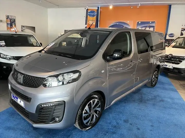 Vue 3/4 avant droite d'un FIAT Scudo cabine approfondie gris Artense métallisé avec jantes alliage et vitres teintées en showroom.