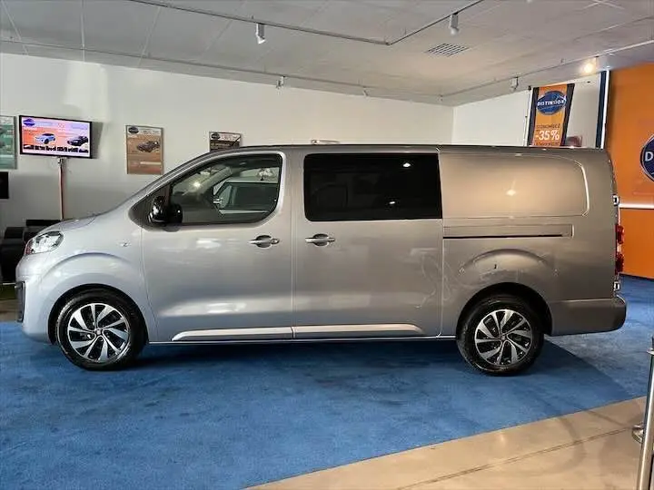 Vue de profil côté gauche d'un FIAT Scudo cabine approfondie gris Artense métal avec vitres teintées arrière en showroom.