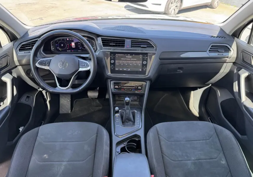 Intérieur avant du Volkswagen Tiguan 2021, tableau de bord noir avec volant multifonctions et console centrale moderne.