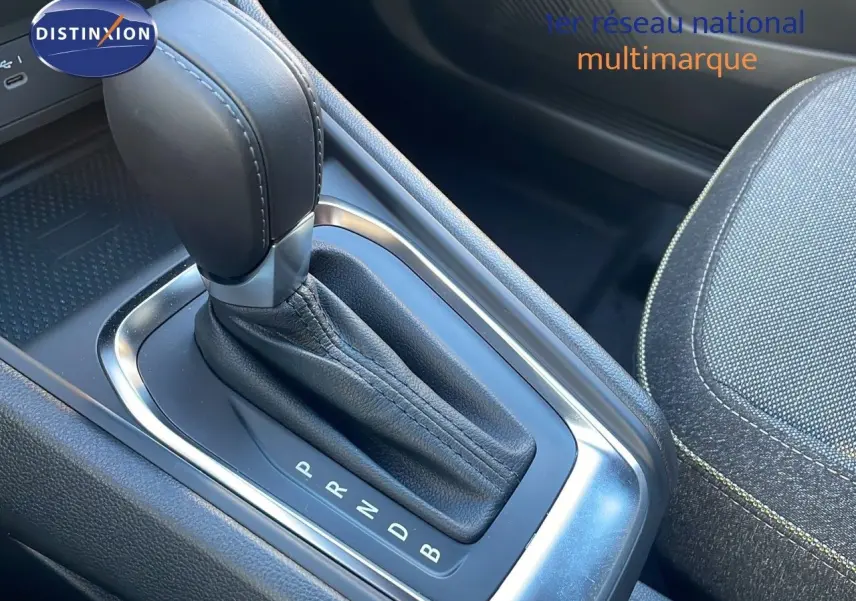 Le levier de vitesses automatique en cuir noir du Renault Captur E-Tech hybride, avec siège tissu gris visible à côté.