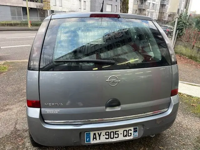 Vue arrière d'une Opel Meriva grise de 2010 avec hayon et plaque d'immatriculation française visible.