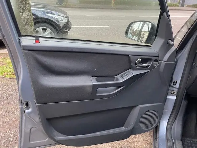 Vue intérieure de la porte avant gauche grise d'une Opel Meriva A Ph2 2010, avec commandes électriques et haut-parleur intégré.