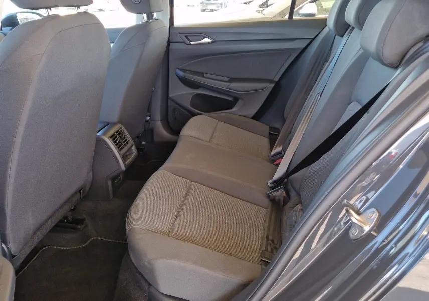 Vue côté droit de l'intérieur arrière gris d'une Volkswagen Golf A8 2023 avec sièges tissu et aérateurs centraux.