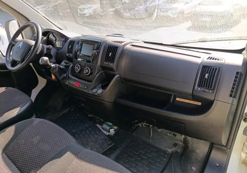 Vue intérieure côté conducteur du tableau de bord noir du Citroën Jumper blanc avec commandes manuelles et écran central.