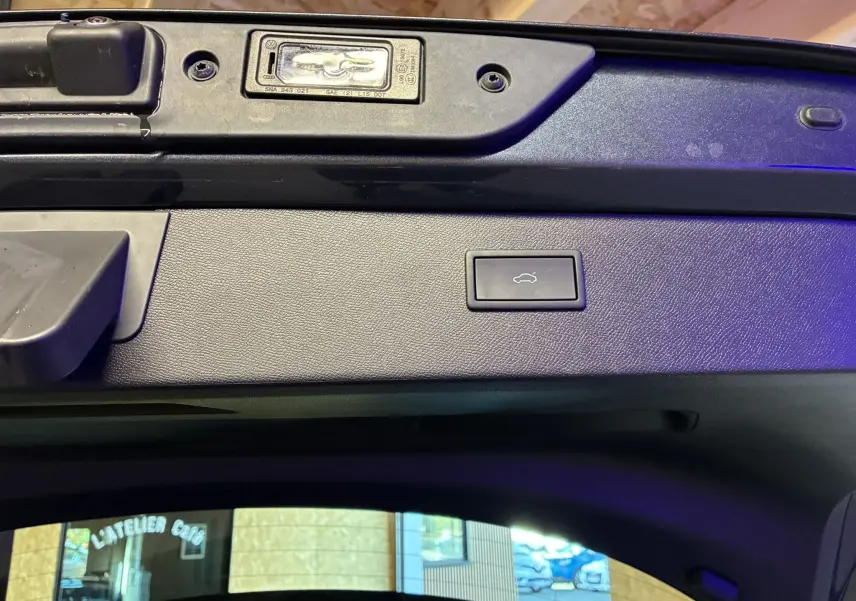 Bouton d'ouverture du coffre sur la partie intérieure de la porte arrière d'un CUPRA Formentor gris foncé, vue rapprochée.