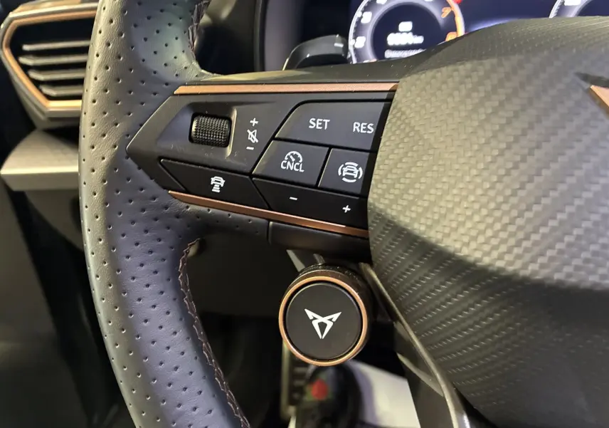 Gros plan sur la partie gauche du volant en cuir perforé gris foncé du CUPRA Formentor 2024 avec commandes intégrées.