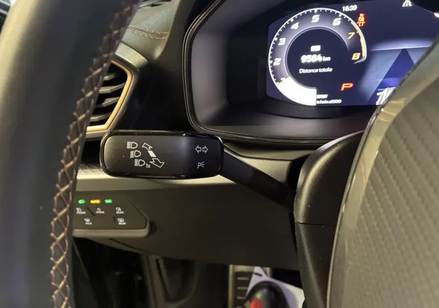 Gros plan sur le levier de clignotant et le tableau de bord numérique du CUPRA Formentor gris foncé, intérieur noir.