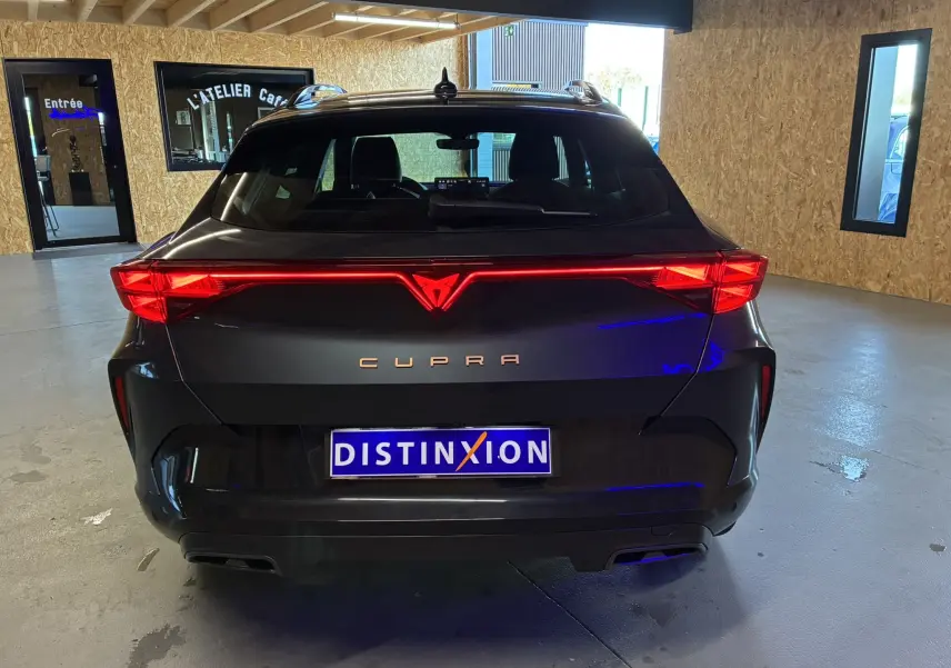 Vue arrière d'une CUPRA Formentor gris foncé avec feux LED allumés dans un garage moderne.