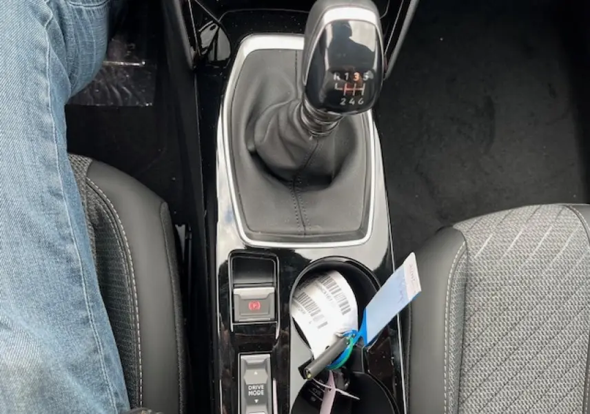 Vue plongeante sur la console centrale du Peugeot 2008 blanc, mettant en valeur le levier de vitesses manuel et les sièges avant.