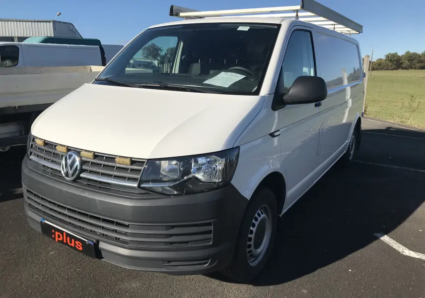 Vue 3/4 avant droit d'un utilitaire Volkswagen Transporter T6 blanc avec pare-chocs noir et galerie de toit.