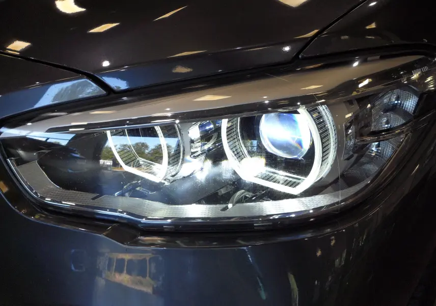 Gros plan sur le phare avant droit d'une BMW Série 1 F21 LCI gris métallisé, mettant en valeur son design LED distinctif.