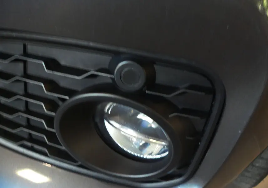 Gros plan sur le feu antibrouillard avant droit et la calandre noire d'une BMW Série 1 F21 LCI gris métallisé.