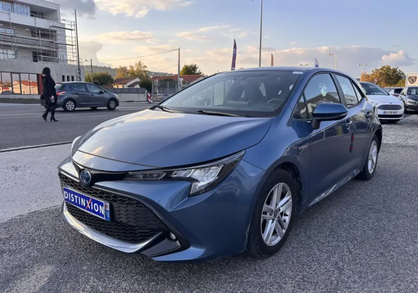 Toyota Corolla hybride bleu clair vue 3/4 avant droit avec calandre noire et jantes argentées.