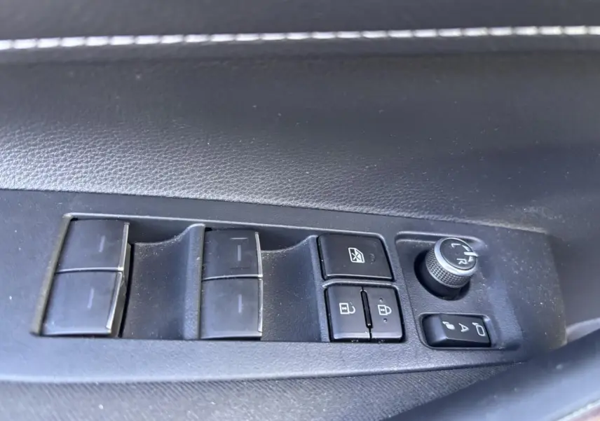 Panneau de commandes des vitres et rétroviseurs côté gauche intérieur d'une Toyota Corolla hybride bleu clair 2020.