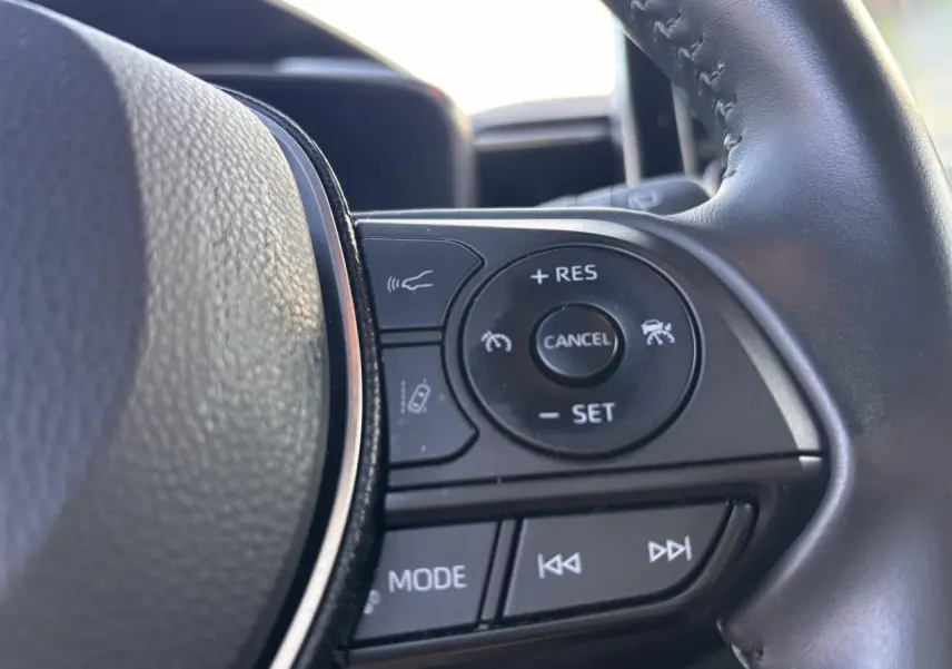 Gros plan sur les commandes au volant droit de la Toyota Corolla Hybride 2020, finition Dynamic Business, avec boutons de régulateur et multimédia.