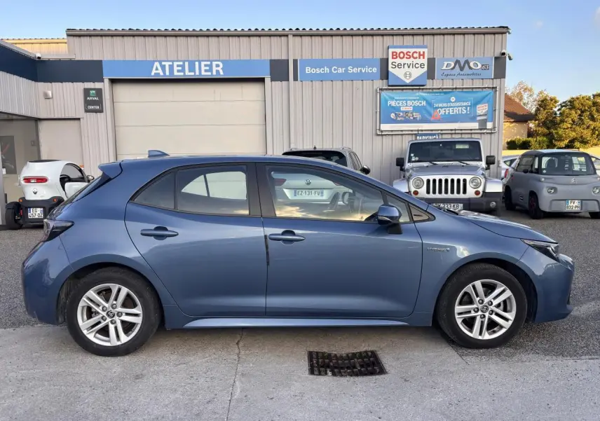 Profil côté gauche de la Toyota Corolla hybride 2020 bleu clair garée devant un atelier Bosch Car Service.