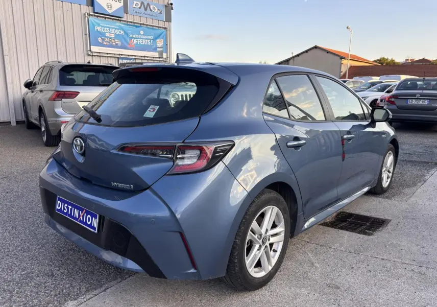 Vue 3/4 arrière droite d'une Toyota Corolla hybride bleu clair 2020 avec feux arrière LED et jantes alliage.