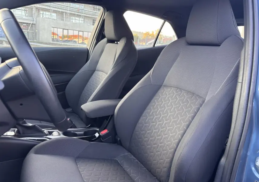 Vue intérieure des sièges avant en tissu gris avec motifs géométriques dans une Toyota Corolla bleu clair 2020 hybride.