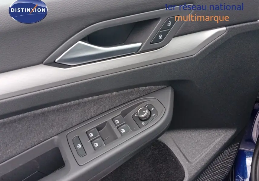 Gros plan sur la porte côté conducteur de la Volkswagen Golf VIII bleu Atlantique, montrant les commandes des vitres et rétroviseurs.