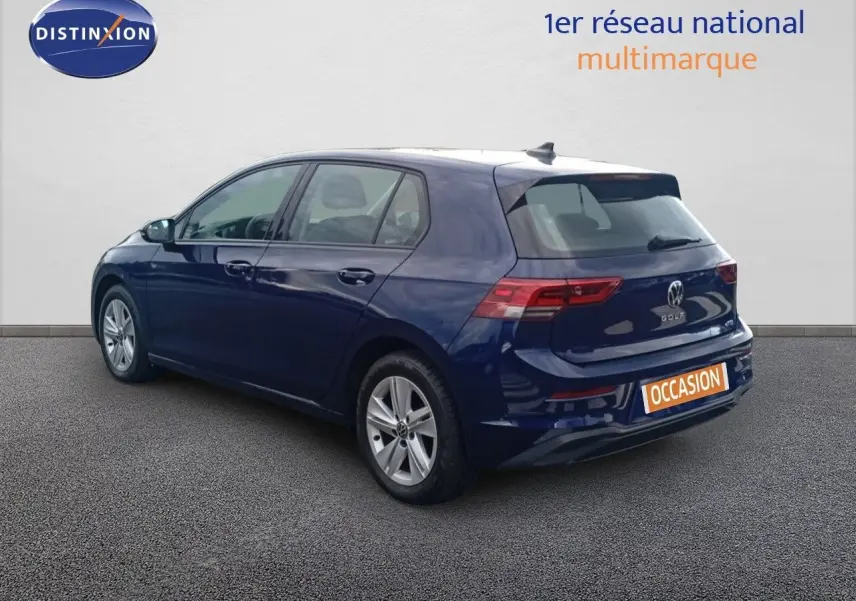 Volkswagen Golf VIII bleu Atlantique métal vue 3/4 arrière côté gauche sur sol gris devant un mur blanc.