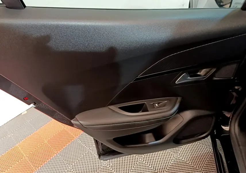 Vue intérieure du panneau de porte avant droit noir du Peugeot 2008 avec commandes de vitre et finition sobre.