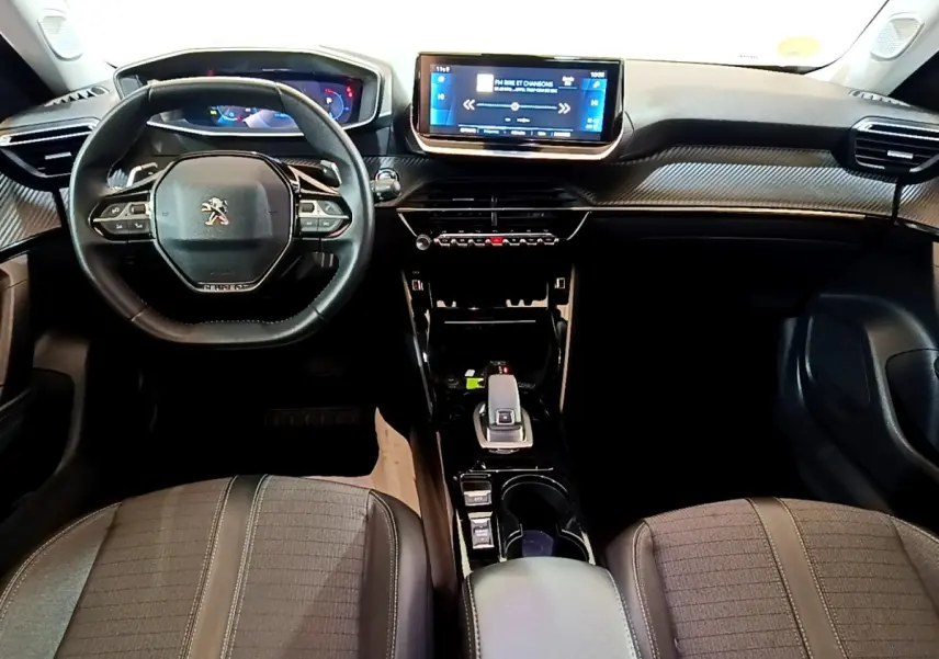 Vue intérieure frontale du tableau de bord du Peugeot 2008 noir, avec écran tactile central et volant multifonctions en cuir.
