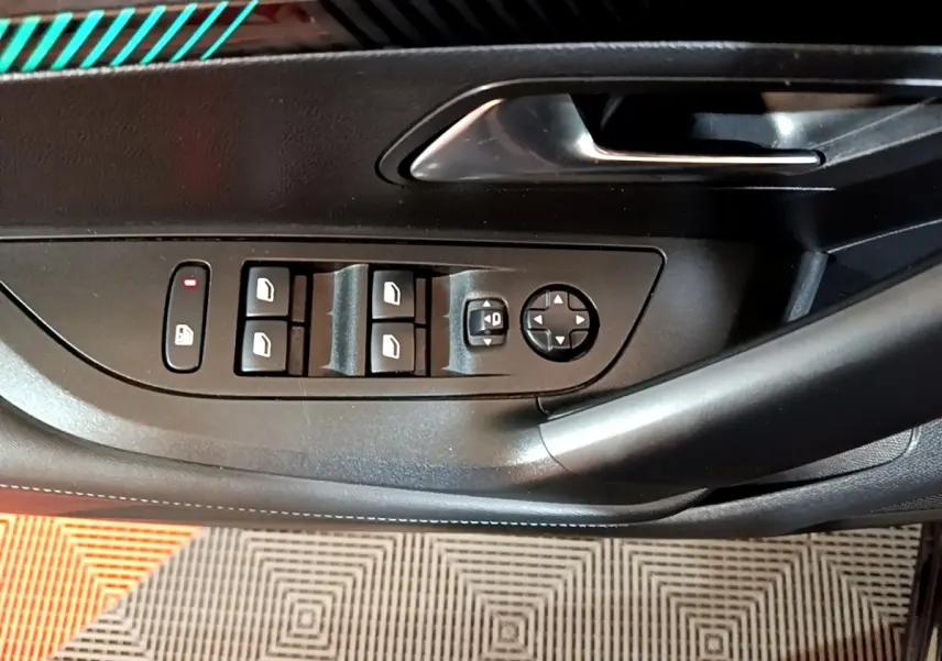 Gros plan sur la commande des vitres et rétroviseurs côté conducteur d’une Peugeot 2008 noire, intérieur noir.