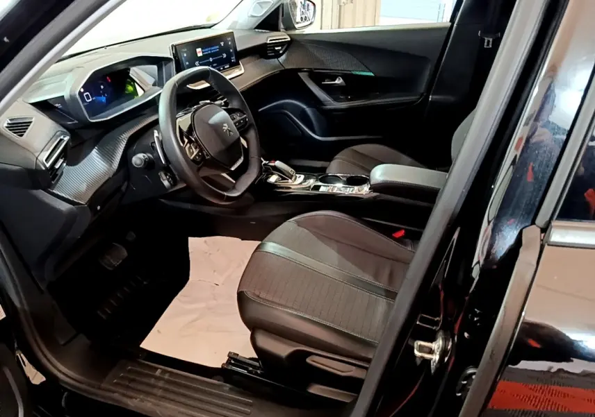 Intérieur avant droit du Peugeot 2008 noir 2021, volant cuir, écran tactile 10 pouces et sièges tissu gris.