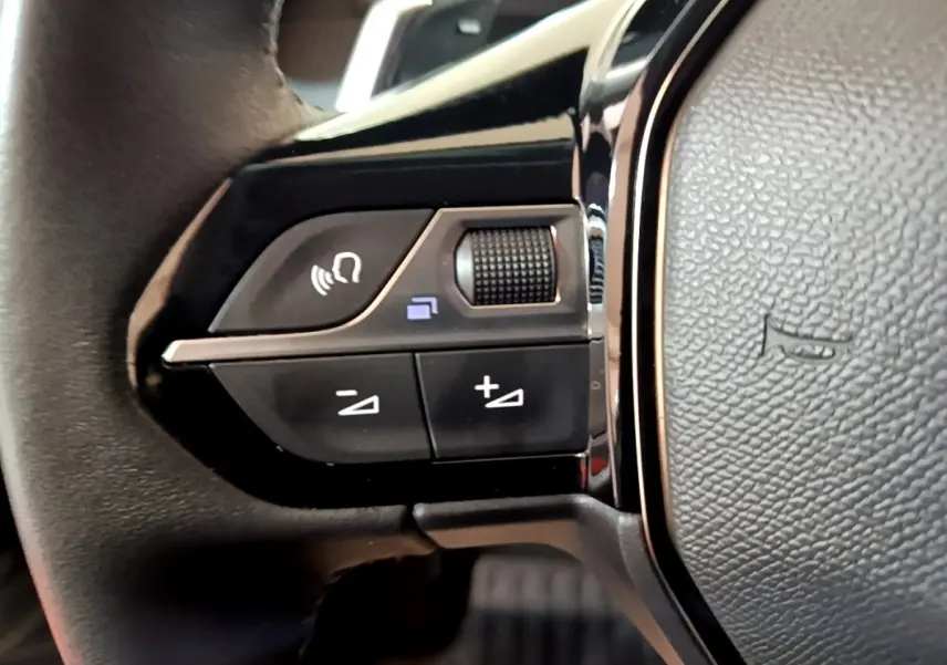 Gros plan sur les commandes gauche du volant cuir noir du Peugeot 2008 2021 version BlueHDi 130 Allure Business.