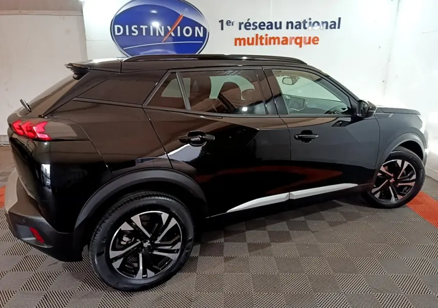 Peugeot 2008 noir vue de profil droit en intérieur, soulignant ses jantes noires et feux arrière LED distinctifs.