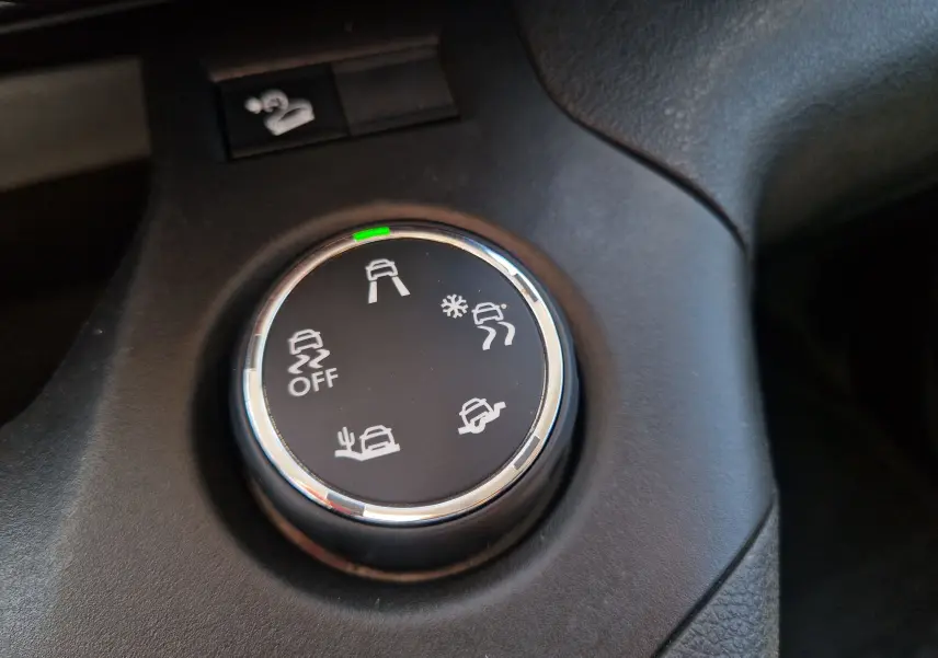 Gros plan sur le sélecteur de modes de conduite noir du tableau de bord du Citroën Berlingo blanc, avec icônes de traction.