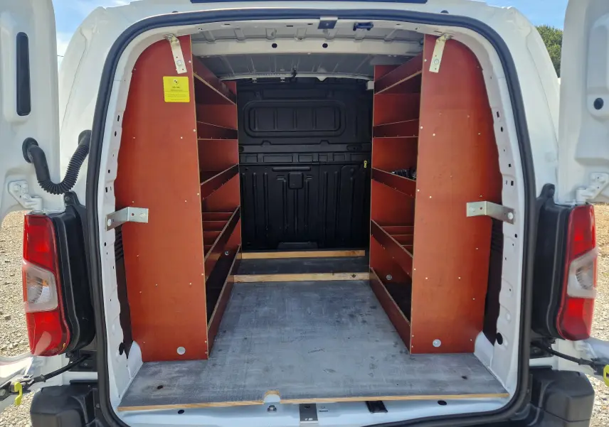 Vue arrière ouverte du Citroën Berlingo blanc 2020, montrant les étagères en bois intégrées dans l’espace de chargement.