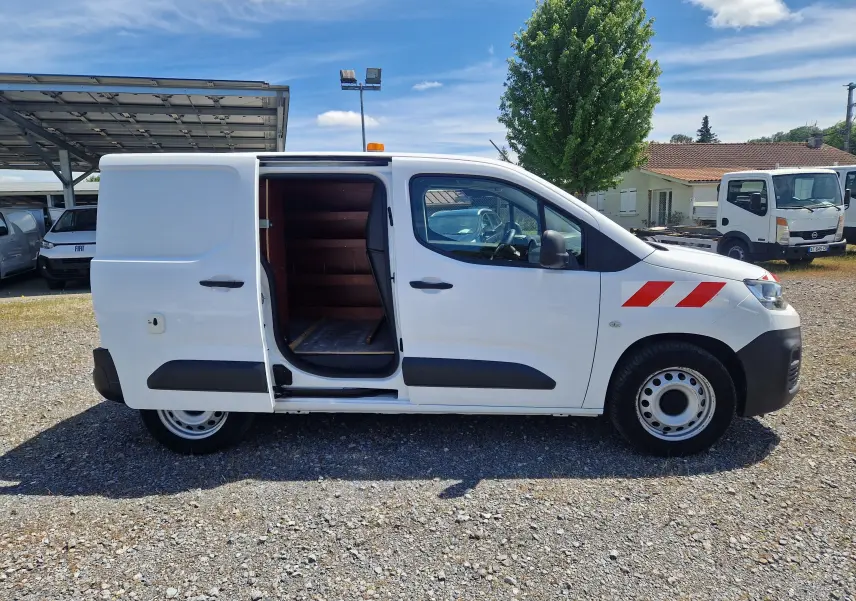 Vue de profil côté droit d’un utilitaire Citroën Berlingo blanc 2020 avec porte coulissante ouverte et gyrophare orange sur le toit.