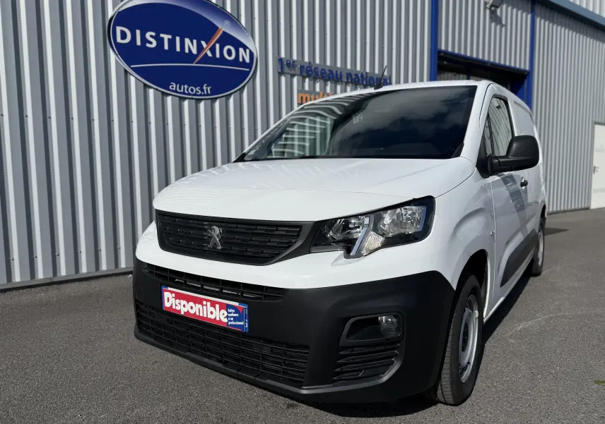 Peugeot Partner blanc en 3/4 avant droit, utilitaire avec pare-chocs noir et calandre noire distinctive.