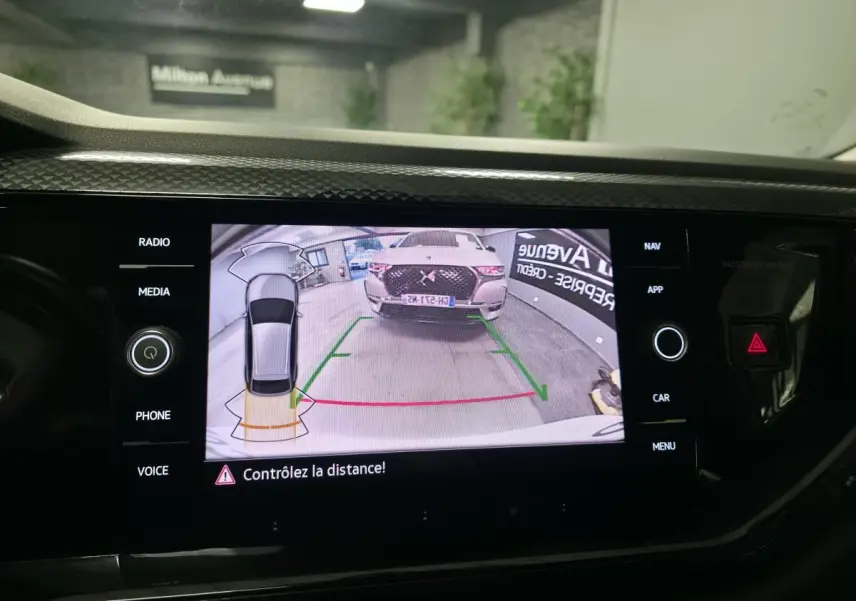 Écran tactile intérieur montrant la caméra de recul avec vue arrière d'un SUV blanc en garage.