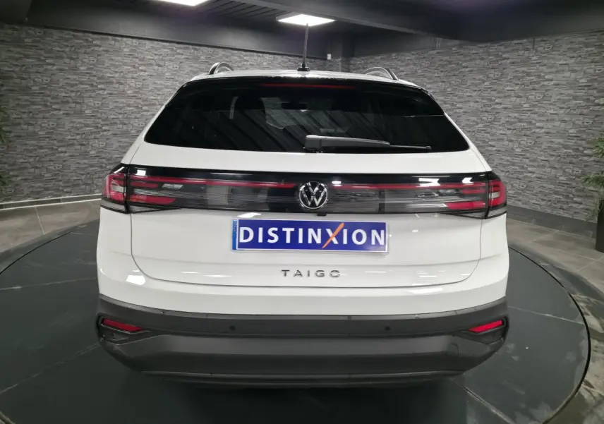 Vue arrière d'un Volkswagen Taigo blanc avec feux arrière reliés par une bande noire brillante.