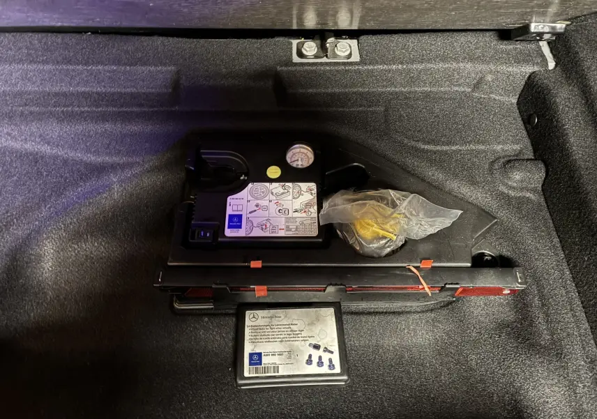 Gros plan sur le compresseur et kit de réparation de pneu dans le coffre d'une Mercedes Classe A 250 AMG Sport gris.
