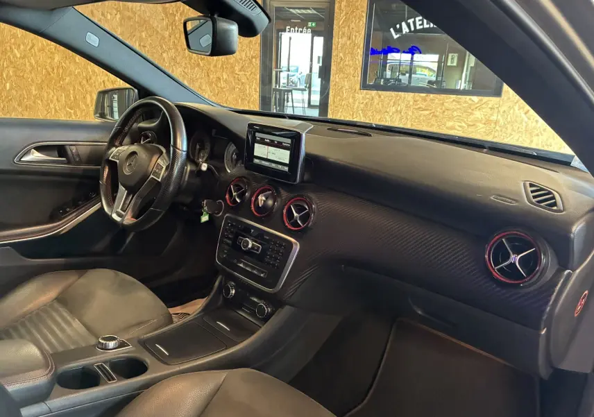 Intérieur noir de la Mercedes Classe A 250 AMG Sport 2014, vue côté conducteur avec tableau de bord et écran central visibles.