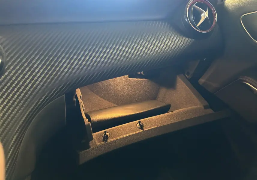 Intérieur de la Mercedes Classe A 250 AMG Sport 2014, boîte à gants ouverte sous tableau de bord gris à effet carbone.