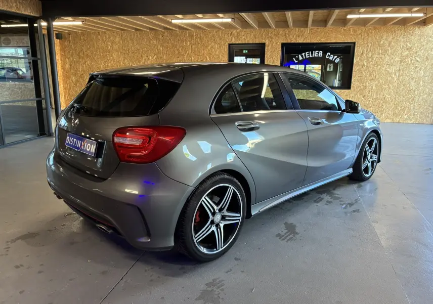 Vue 3/4 arrière droite d'une Mercedes Classe A 250 AMG Sport gris métallisé avec jantes alliage bicolores en intérieur d'atelier.