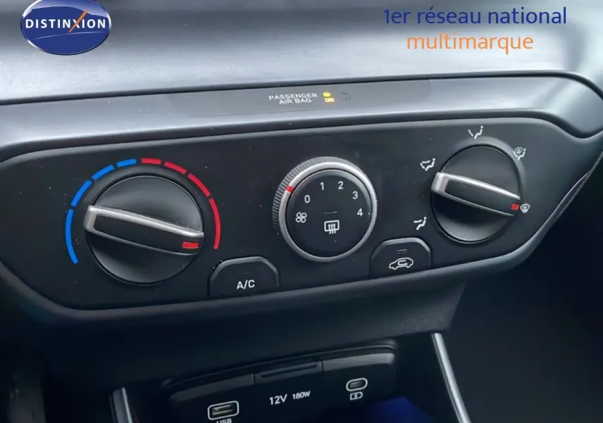 Gros plan sur les commandes de climatisation manuelle et les ports USB d'une Hyundai i20 rouge Dragon Metal 2025.