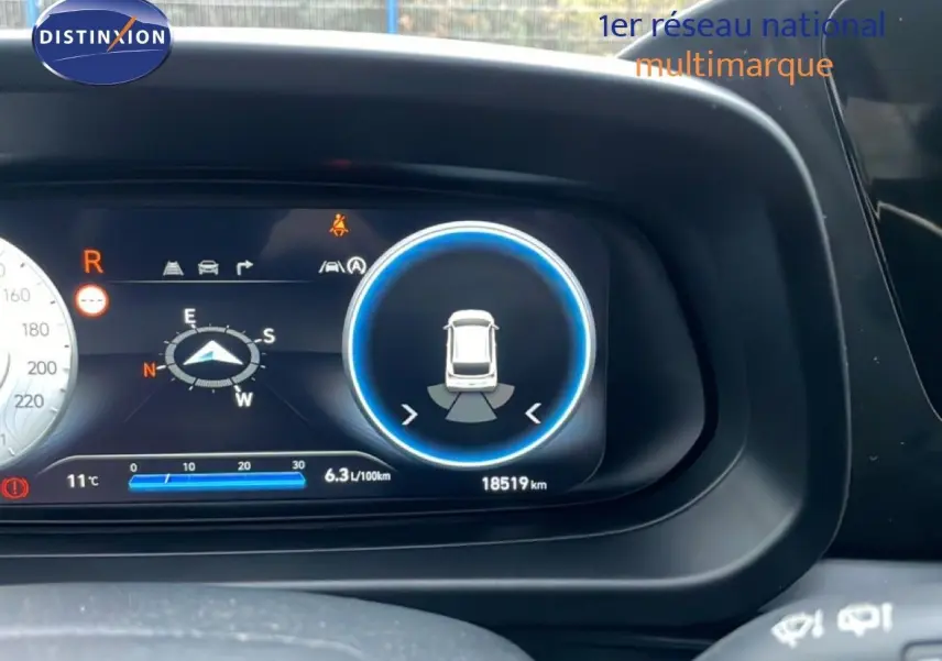 Gros plan sur le tableau de bord numérique de la Hyundai i20 2025 rouge Dragon Metal, affichant la consommation et le compteur kilométrique.