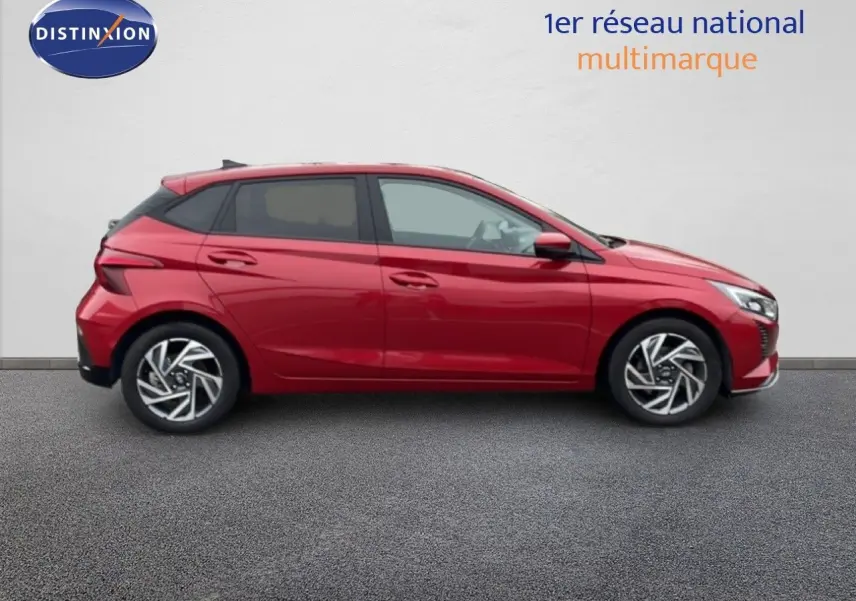 Profil côté gauche d'une Hyundai i20 2025 rouge dragon métal avec jantes alliage et lignes dynamiques marquées.