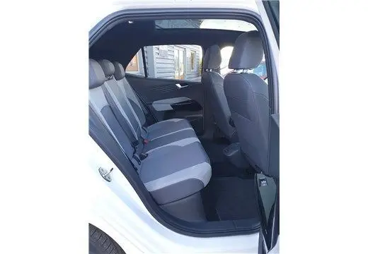 Vue intérieure côté gauche arrière d'un Volkswagen ID.3 blanc glacier montrant les sièges arrière en tissu bicolore gris et noir.