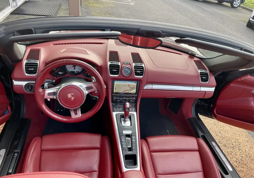 Vue intérieure avant de la Porsche Boxster S 981 2012 avec tableau de bord et sièges en cuir rouge grenat.