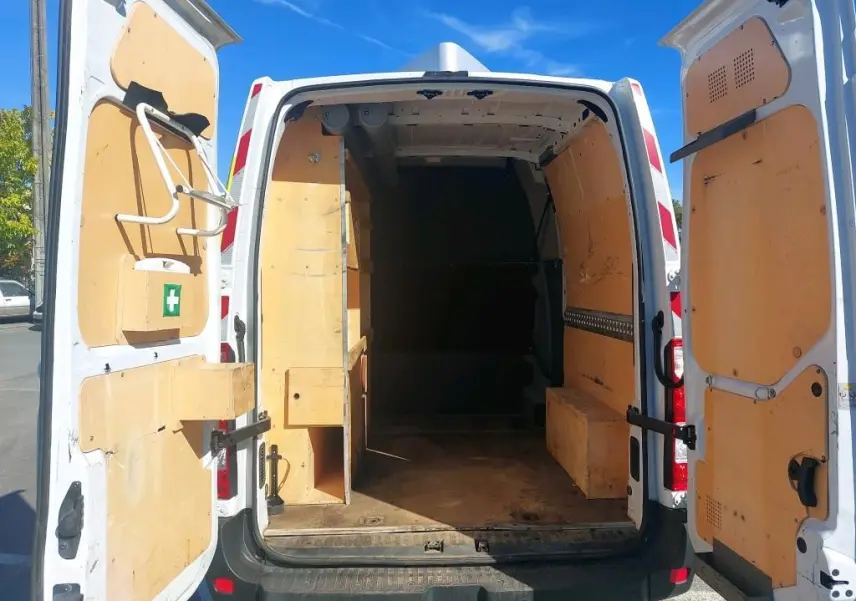 Vue arrière du Renault Master blanc avec portes ouvertes, montrant l'intérieur utilitaire en bois clair.