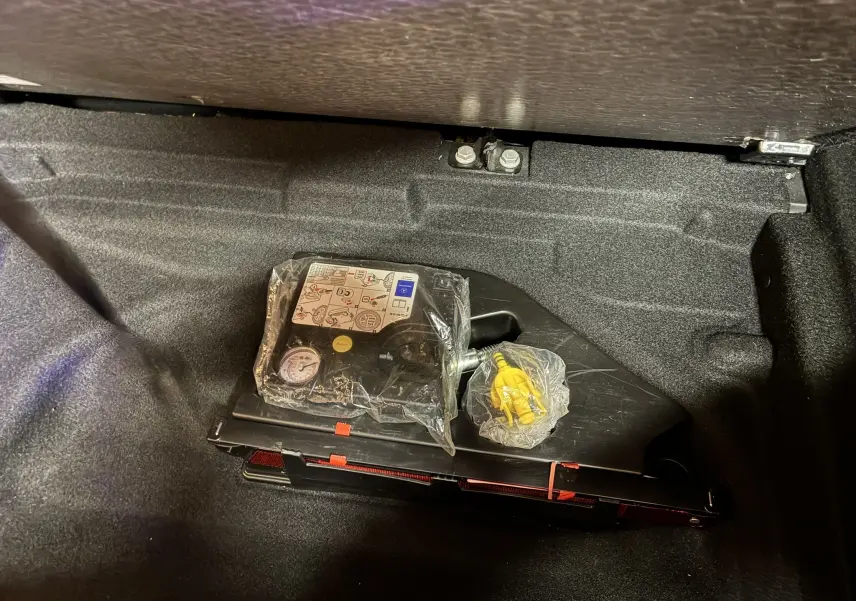 Compresseur de pneu et kit de réparation dans le coffre d'une Mercedes Classe A 180 CDI noir de 2018.